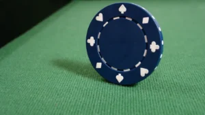 Uma ficha de poker sem número em pé em uma mesa forrada com tapete verde